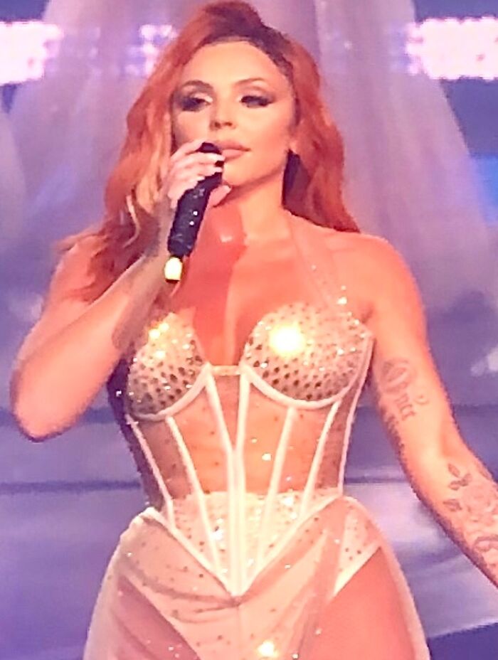 Mulher com um espartilho brilhante segurando um microfone no palco, representando desastres de relações públicas e desafios de relações públicas.