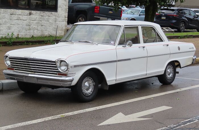 White classic car parked on wet street with several other vehicles in background, illustrating PR disasters scene.