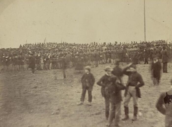 Old photograph showing a large crowd and children, capturing a strange moment that hints at time travel theories.