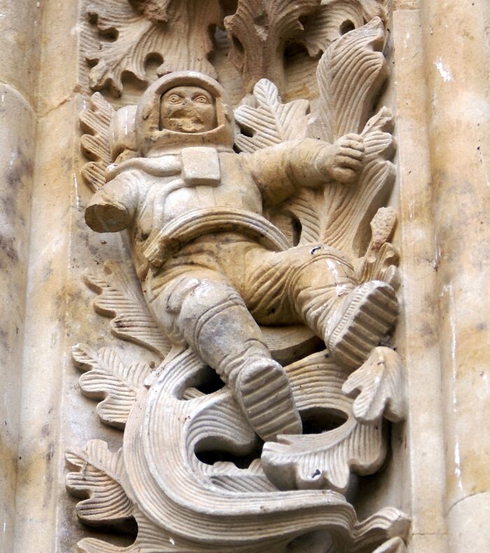 Stone carving of a figure resembling an astronaut surrounded by ornate leaves, showcasing strange details in old photographs.