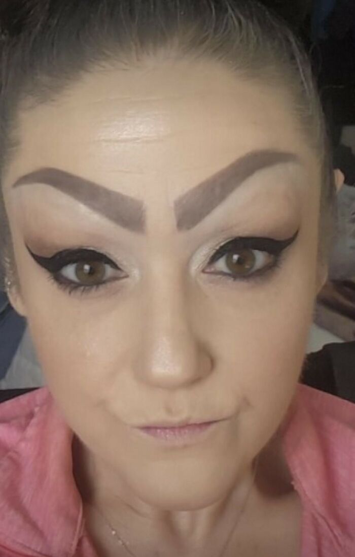 Close-up of a woman with crazy eyebrows styled in thick, angular shapes and bold eye makeup on her face.
