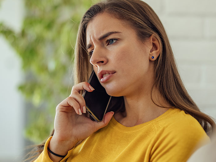 Woman looking concerned while speaking on phone, illustrating situation of detention by ICE in a parking lot. Woman looking concerned while speaking on phone, illustrating situation of detention by ICE in a parking lot.