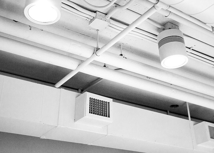 White ceiling pipes and vents with lighting fixtures in a modern industrial interior, illustrating fake facts from movies.