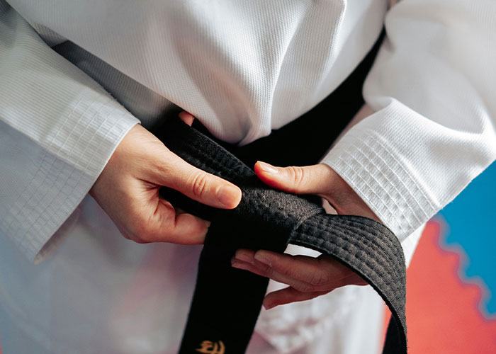 Person tying a black martial arts belt, illustrating fake facts people believed only because of movies.