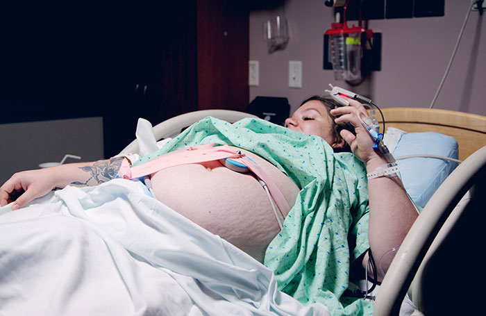 Pregnant woman in hospital bed with monitoring belts, illustrating fake facts people believed only because of movies.