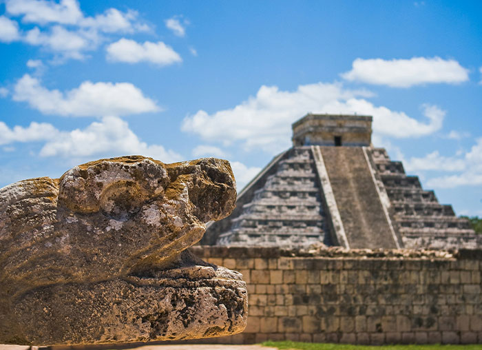 Ancient stone sculpture of a serpent head with a stepped pyramid in the background, illustrating fake facts from movies.