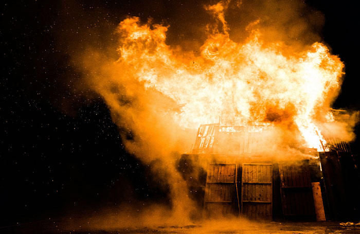 A large fiery explosion engulfing a wooden structure, illustrating fake facts people believed because of movies.