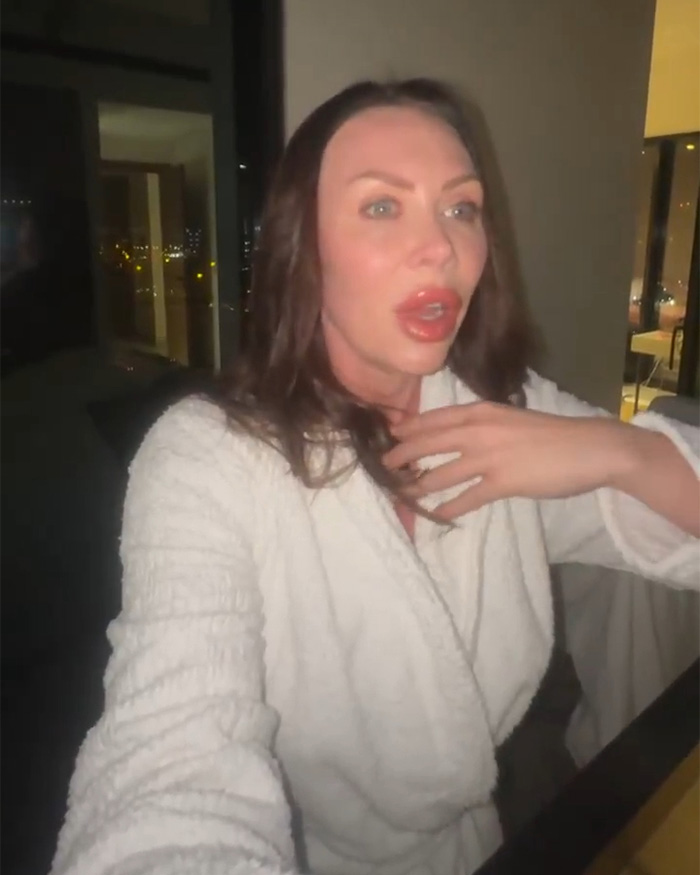 Female influencer filming herself indoors at night, sparking controversy amid Iran Dubai strikes and public outrage.