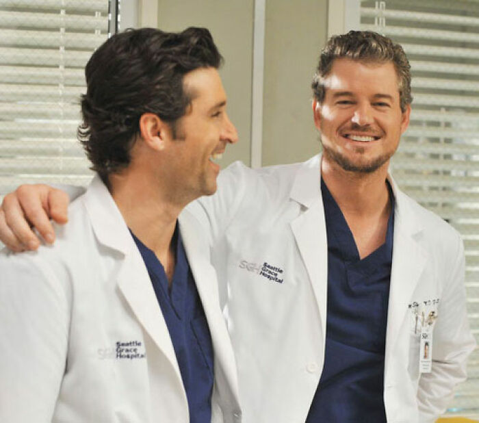 Two male doctors in white coats smiling and talking in a hospital setting related to Shonda Rhimes defending Oscars decision.