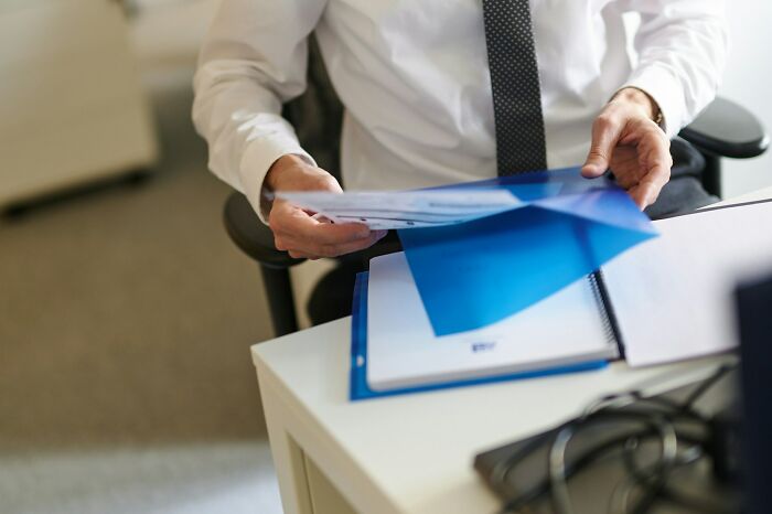 Businessman in white shirt reviewing documents at office desk highlighting shaky industries risk and uncertainty.