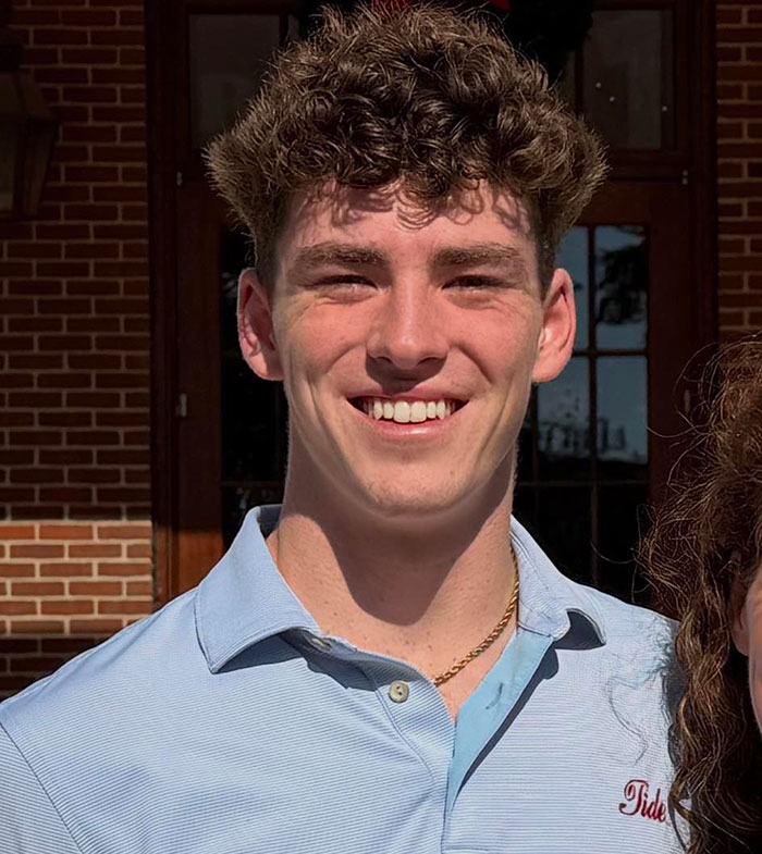 Young man smiling outdoors in front of a brick building, linked to suspicious footage in mysterious vanishing of American student in Spain.