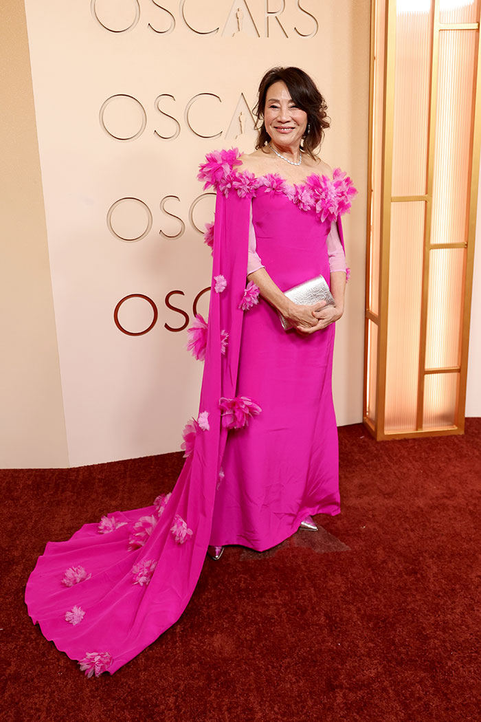 Woman in a vibrant pink floral gown posing on the red carpet showcasing one of the most outrageous and disastrous looks from the Oscars 2026.
