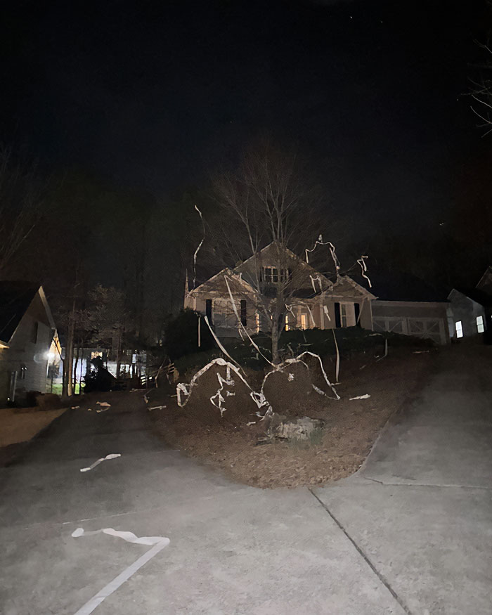 Nighttime view of a suburban house covered in prank decorations linked to high school teacher prank incident.