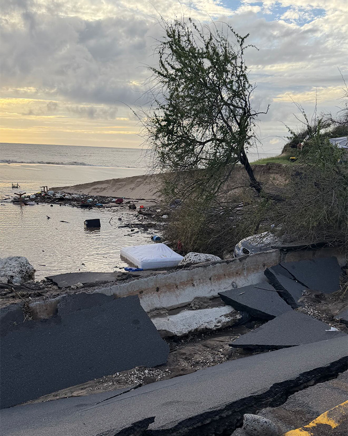 Danos causados ​​por inundações no Havaí com estradas quebradas, detritos espalhados e uma árvore inclinada perto da costa após inundações e evacuações históricas.
