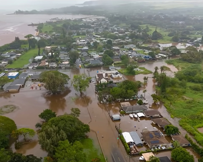 Vista aérea de enchentes históricas que causaram evacuações em massa no Havaí, com casas e ruas submersas na água.