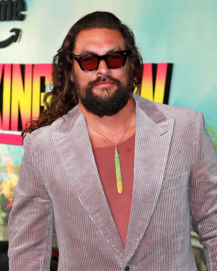 Jason Momoa usando óculos escuros e uma jaqueta de veludo cotelê em meio a enchentes históricas que causaram evacuações em massa no Havaí.