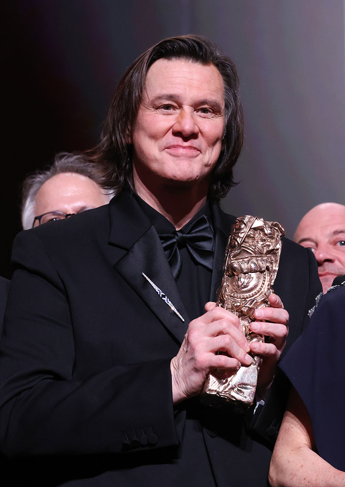 Jim Carrey holding an award, showcasing details of his new face and revealing the actor’s cause of sadness.
