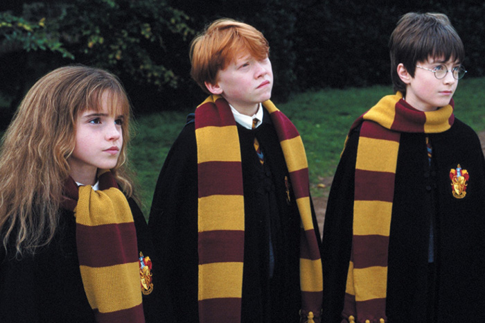 Three young Hogwarts students in Gryffindor scarves outdoors, relating to Harry Potter reboot and J.K. Rowling opinions. Three young Hogwarts students in Gryffindor scarves outdoors, relating to Harry Potter reboot and J.K. Rowling opinions.