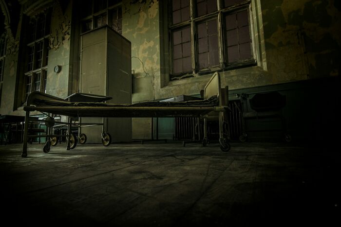 Abandoned hospital room with eerie atmosphere, an old bed, and peeling walls, capturing urban explorers’ terrifying moments.