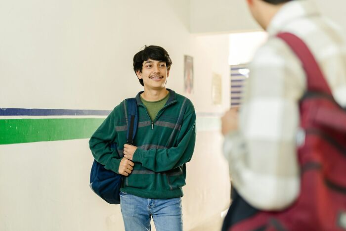 Teen student smiling and carrying backpack in hallway, illustrating moments people destroyed their own lives in an instant.
