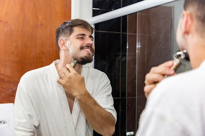 Man shaving and smiling in front of bathroom mirror, reflecting loss of faith in the justice system moments shared by jurors