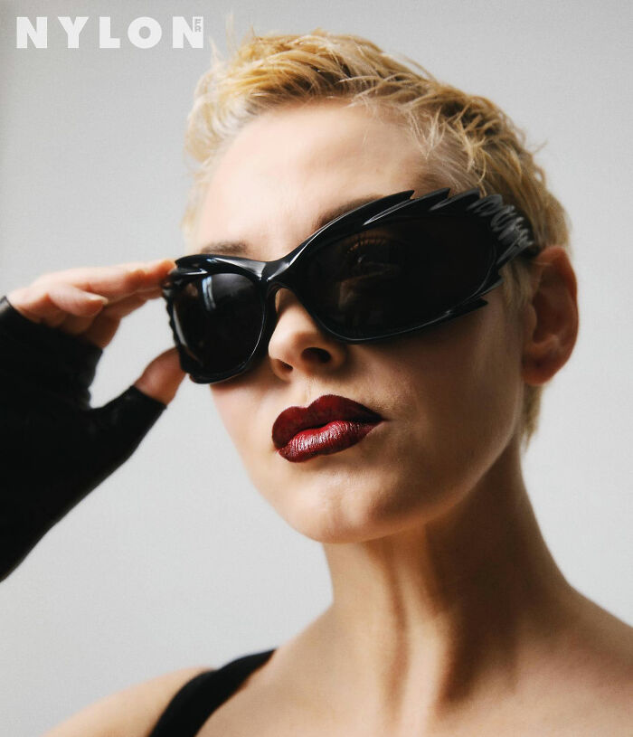 Woman with short blonde hair wearing black sunglasses and dark red lipstick, styled with edgy fashion for a bold look. Woman with short blonde hair wearing black sunglasses and dark red lipstick, styled with edgy fashion for a bold look.