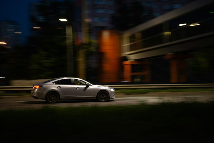 Silver car driving fast at night on an urban road, capturing one of the scariest experiences people still can't believe.