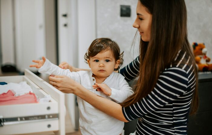 Woman gently helping toddler get dressed, illustrating forgiveness and moving forward after cheating spouse issues.