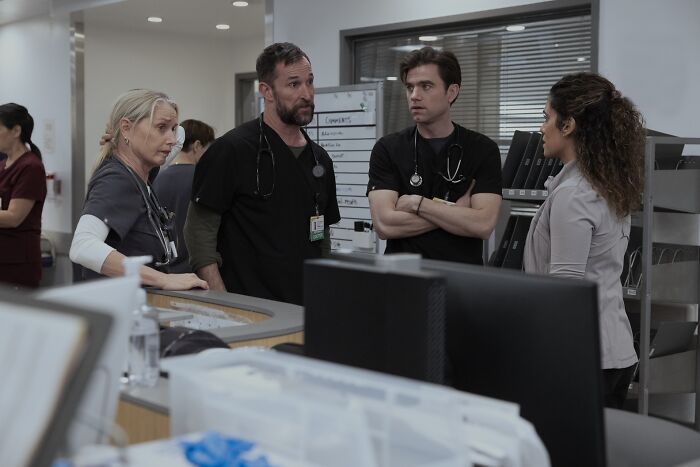 Doctors in a hospital discussing a case in The Pitt Season 2, Episode 12 preview scene with medical equipment around.