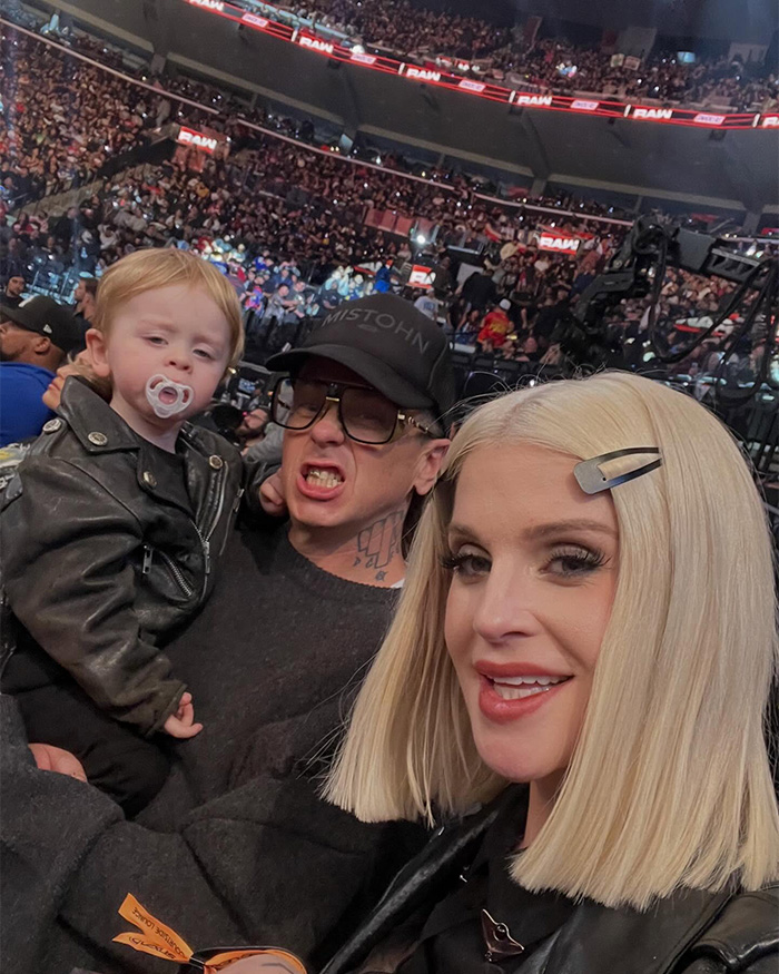 Kelly Osbourne with fiancé Sid Wilson and child at a crowded event, showing her updated blonde hairstyle and makeup.