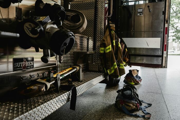 Firefighter gear and equipment beside a fire truck in a station, evoking spooky haunted place experiences.