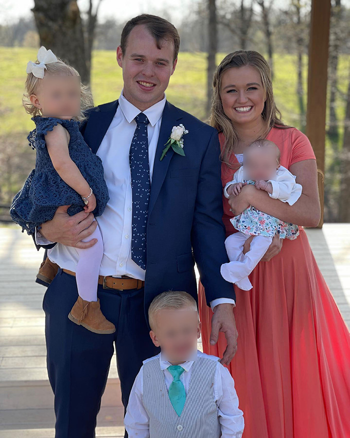 Joseph Garrett Duggar from 19 Kids And Counting posing outdoors with family, dressed formally on a sunny day.