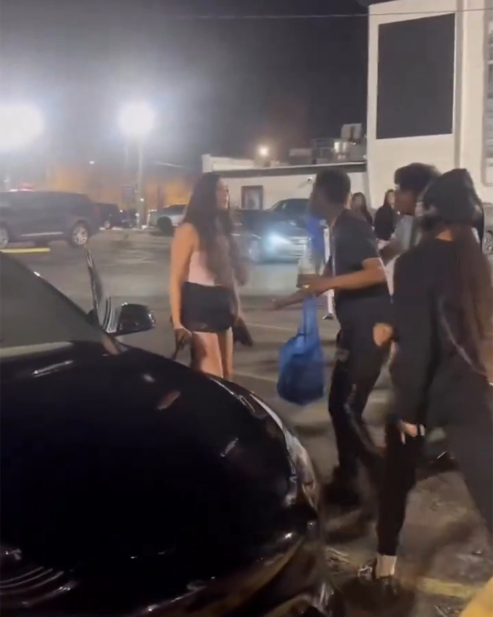 Multidão se reuniu perto de um carro preto em um estacionamento à noite depois que uma mulher de Kentucky foi presa por dirigir contra um incidente com uma multidão