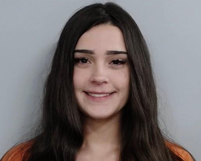 Mulher de Kentucky, de 20 anos, com longos cabelos escuros, sorrindo levemente em uma foto após prisão relacionada a incidente com multidão