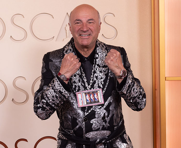 Man wearing a detailed patterned suit posing with clenched fists at the 2026 Oscars cringe moments event.