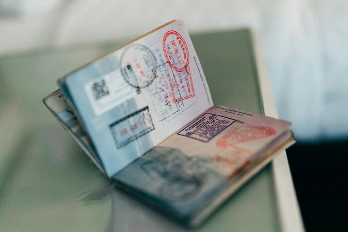 Open passport on a table showing multiple visa stamps, related to stories of payback that feel almost wrong to enjoy.