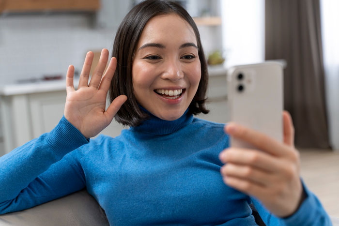 Young woman happily video chatting on smartphone after perfect first date abroad, realizing she deleted dating app.
