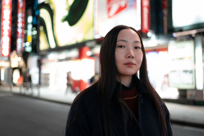 Young woman standing on a city street at night, reflecting on a perfect first date abroad and deleting dating app.