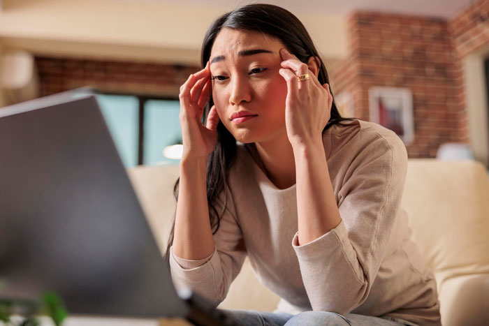 Woman looking stressed while using a laptop, reflecting on a first date abroad and deleting dating app.