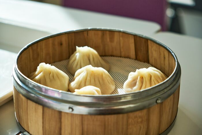 Steamed dumplings in a bamboo basket, illustrating food service and customer complaints making it hard for employees.