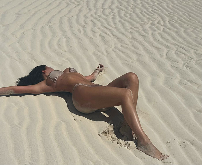 Woman in bikini laying on rippled beach sand, relating to Timothée Chalamet and Kylie Jenner's relationship speculation. Woman in bikini laying on rippled beach sand, relating to Timothée Chalamet and Kylie Jenner's relationship speculation.