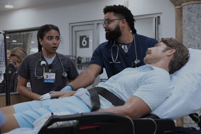 Two nurses attending to a patient on a gurney in a hospital setting from The Pitt Season 2 guest stars.
