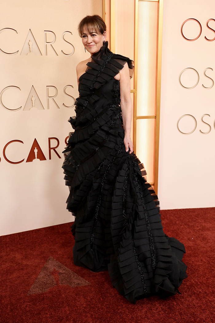Woman wearing a dramatic black ruffled gown posing on the red carpet at the Oscars 2026 in outrageous fashion looks.