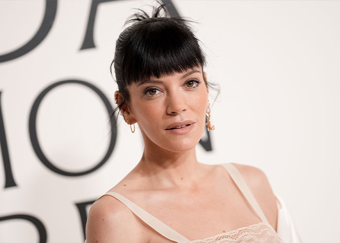 Lily Allen posando em um evento, mostrando os resultados de sua cirurgia plástica em um novo ensaio fotográfico para campanha de lingerie.