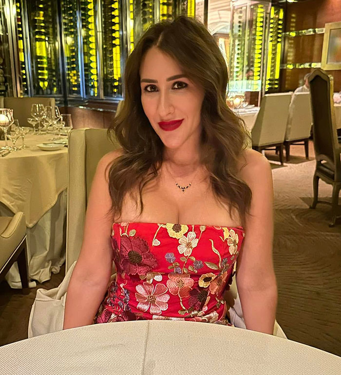 Mulher com vestido vermelho floral sentada à mesa de um restaurante, representando novos detalhes perturbadores no caso de morte violenta de uma enfermeira.