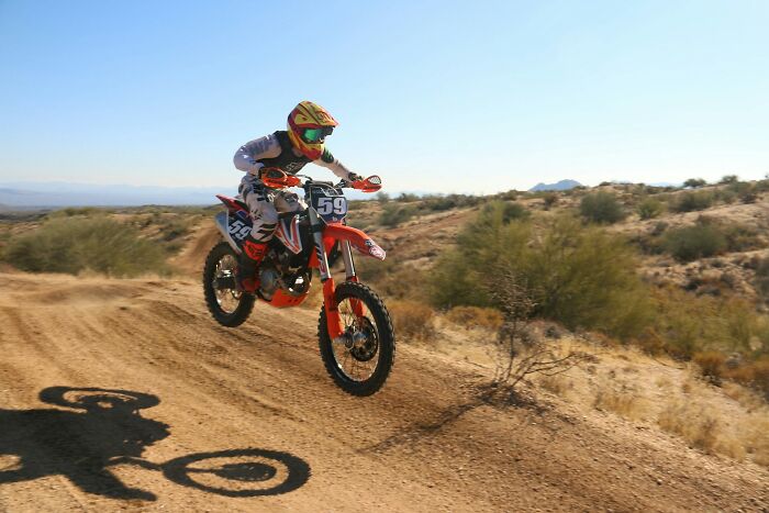 Motocross rider jumping over dirt track in desert, capturing one of the scariest experiences in extreme sports.