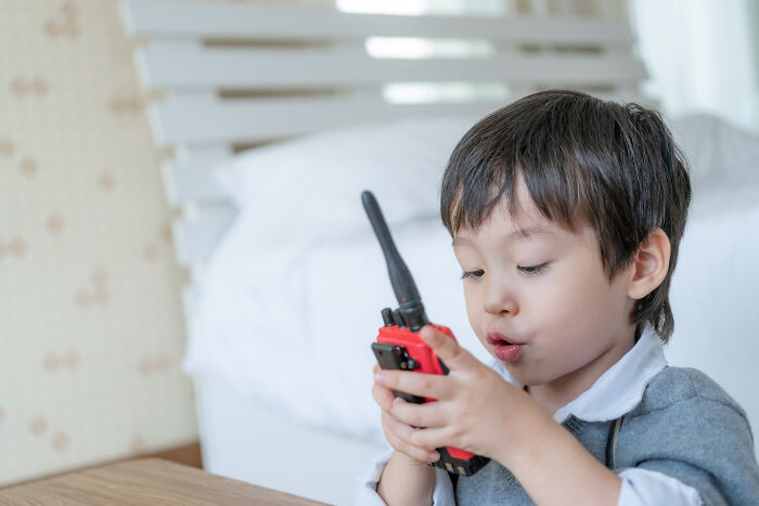Young boy indoors using a red walkie talkie, illustrating themes from scary camping and hiking stories that ended well.