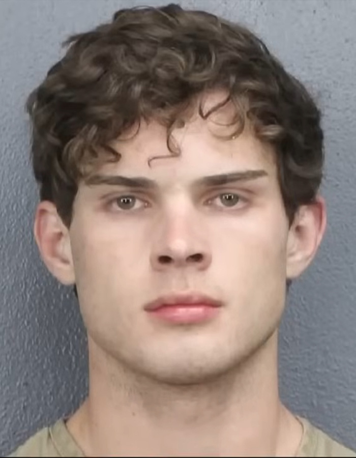 Young man with curly hair and neutral expression in a mugshot photo related to looksmaxxing influencer arrest in Florida.