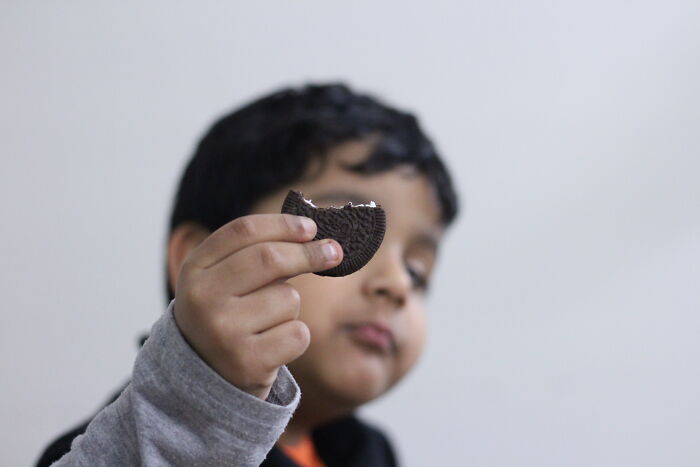 Child holding a bitten chocolate cookie, highlighting wholesome moments dads have their kids’ backs with treats.
