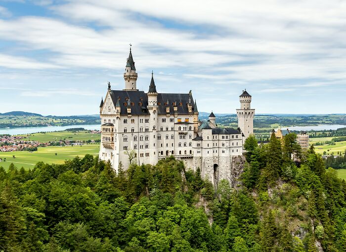 Neuschwanstein Castle perched on a hill surrounded by lush greenery, a famous iconic landmark with popular myths.